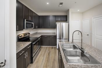 A modern kitchen with black cabinets and stainless steel appliances.